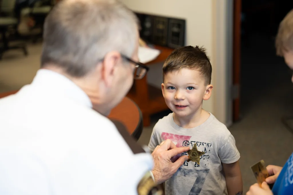A child receiving a sheriff's sticker from a sheriff