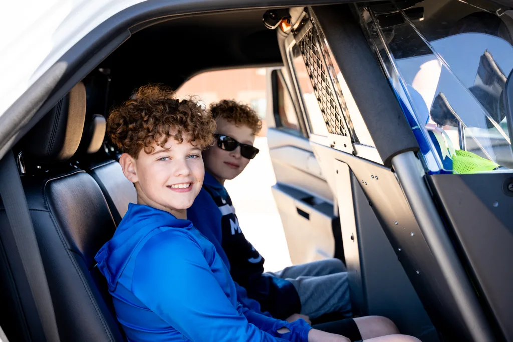 Two young boys seated in the back of a squad car