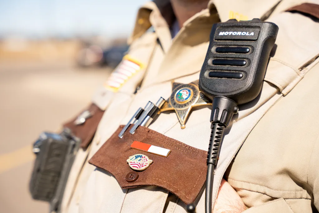 Closeup of a sheriffs badge, uniform and radio